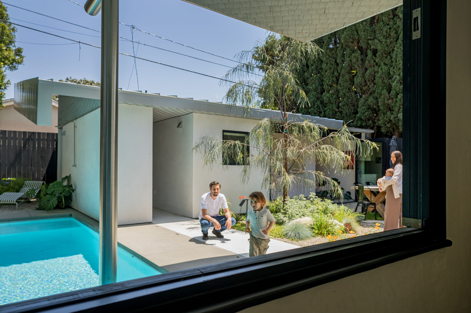 A view of an ADU and pool through a large window.