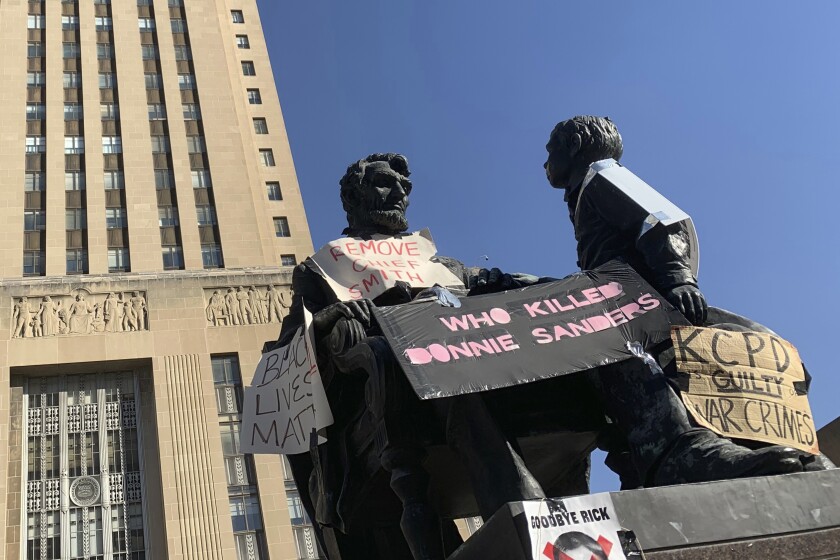 FILE - Protesters have plastered an Abraham Lincoln statue with signs demanding information about the deadly police shooting of Donnie Sanders by a white police officer and the resignation of the police chief, as seen on Oct. 13, 2020, in Kansas City, Mo. The family of a Sanders is suing the officer and the Board of Police Commissioners for at least $10 million. (AP Photo/Heather Hollingsworth, File)