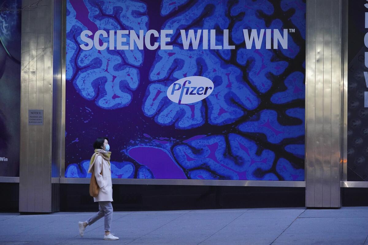A person walks by a big ad that says, "Science will win. Pfizer."