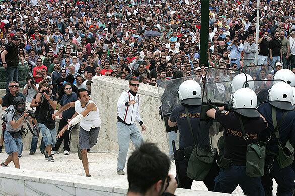 Protesters clash with riot police on the steps of the Greek Parliament during a demonstration in Athens on Wednesday. Three people died in a fire in a bank started by protesters in central Athens, police said, during demonstrations against government austerity measures.