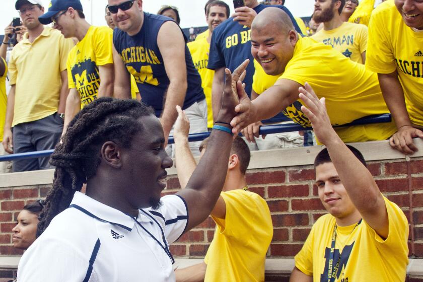 Former Michigan star and high-fives fans as he walk around the field during the fourth quarter of an NCAA college football game between Michigan and Appalachian State, Saturday, Aug. 30, 2014, in Ann Arbor, Mich. Robinson is no longer part of Sherrone Moore's coaching staff, school spokesman Dave Ablauf confirmed. Robinson was suspected of driving while intoxicated after he was in a single-car accident, less than two miles from the football team's training facility. (AP Photo/Tony Ding, File)