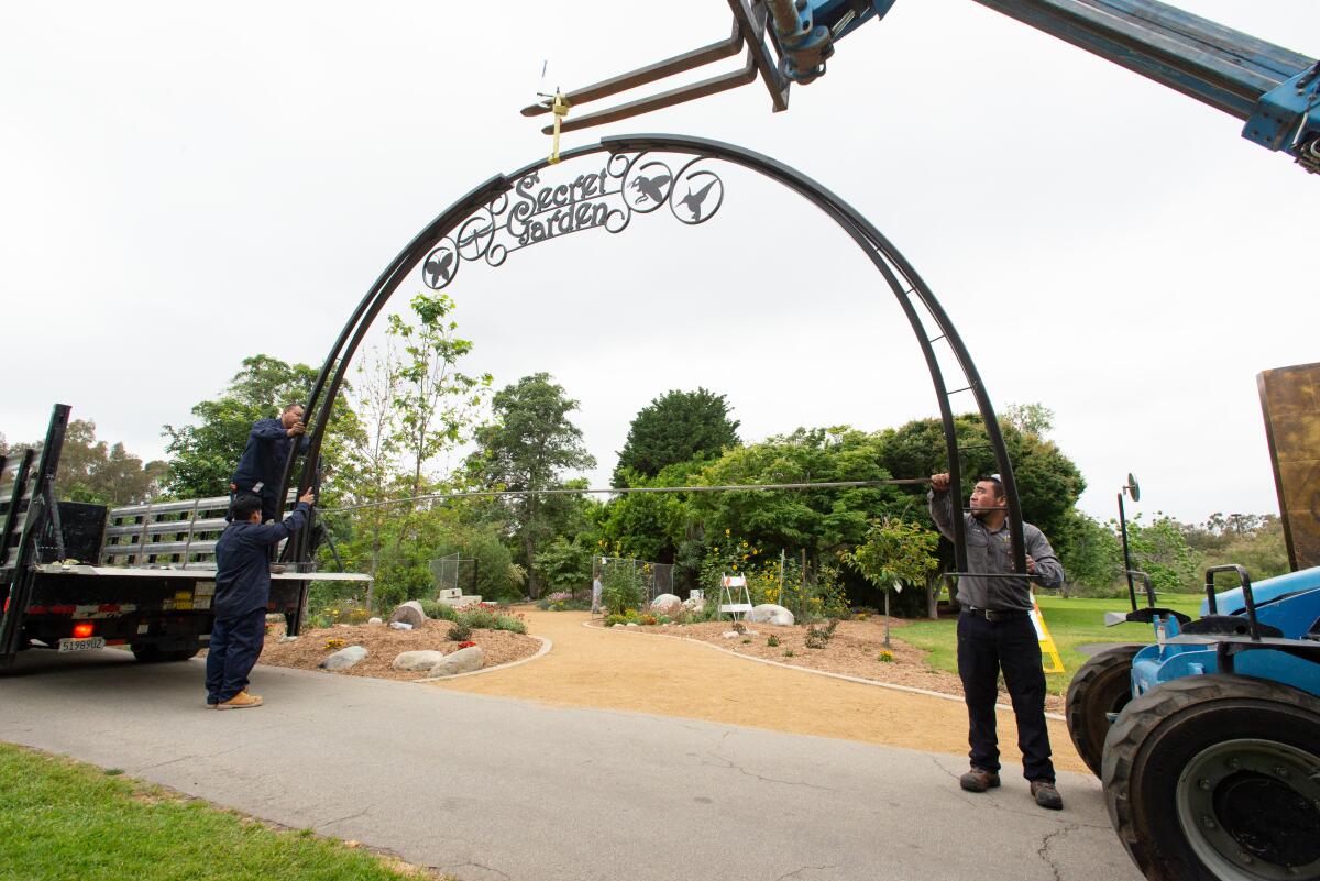 Workers install a new archway at the Secret Garden in Huntington Central Park Friday.