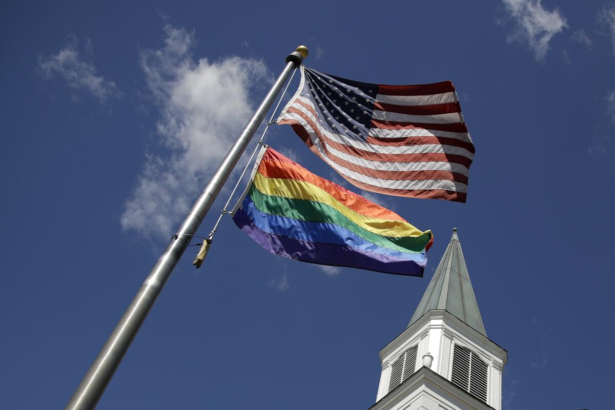 A gay Pride rainbow flag flies with the U.S. flag in front of the Asbury United Methodist Church in Prairie Village, Kan.