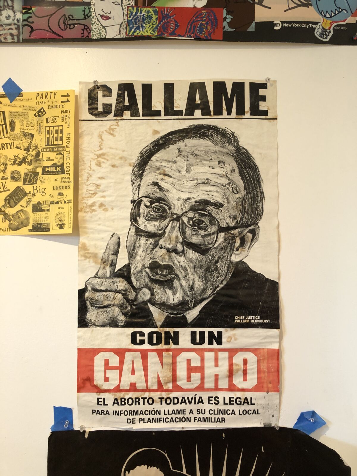 A print fastened to a wall shows Justice William Rehnquist wagging his finger with the words "Callame Con Un Gancho." 