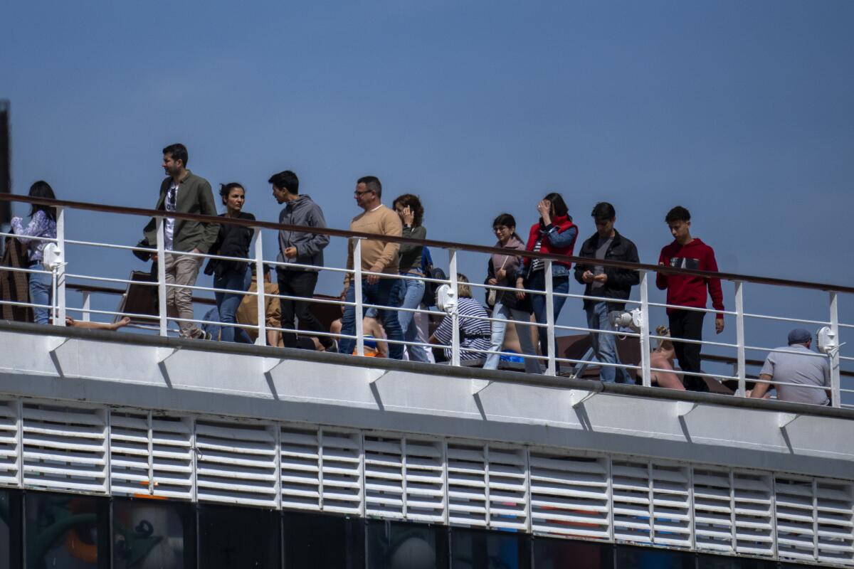 FILE - Passengers are photographed on the cruise ship MSC Armony, moored in the port of Barcelona, Spain, on April 3, 2024. Spain is to deport more than 60 Bolivians who arrived last week by cruise ship in Barcelona but were not allowed to disembark because their visas were false. Spanish government officials said 65 of the 69 Bolivians that arrived would be flown to the Bolivian city of Santa Cruz. (AP Photo/Emilio Morenatti, File)