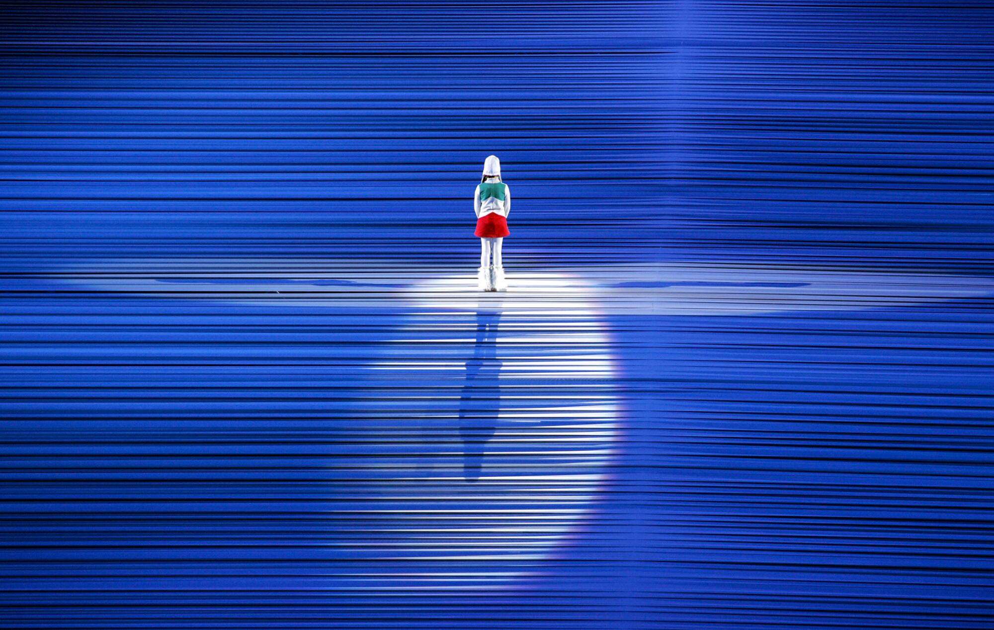 A girl stands in a spotlight on a blue stage
