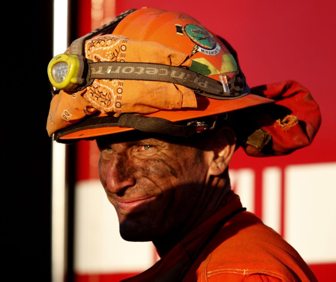A California Department of Forestry and Fire Protection firefighter from Miramonte sports a smile after fighting the blaze in an area along Highway 243.