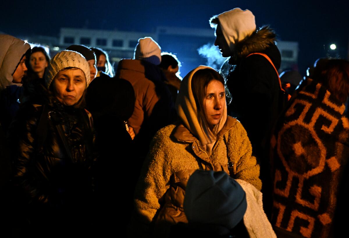 Ukrainian refugees in coats wait for a bus 