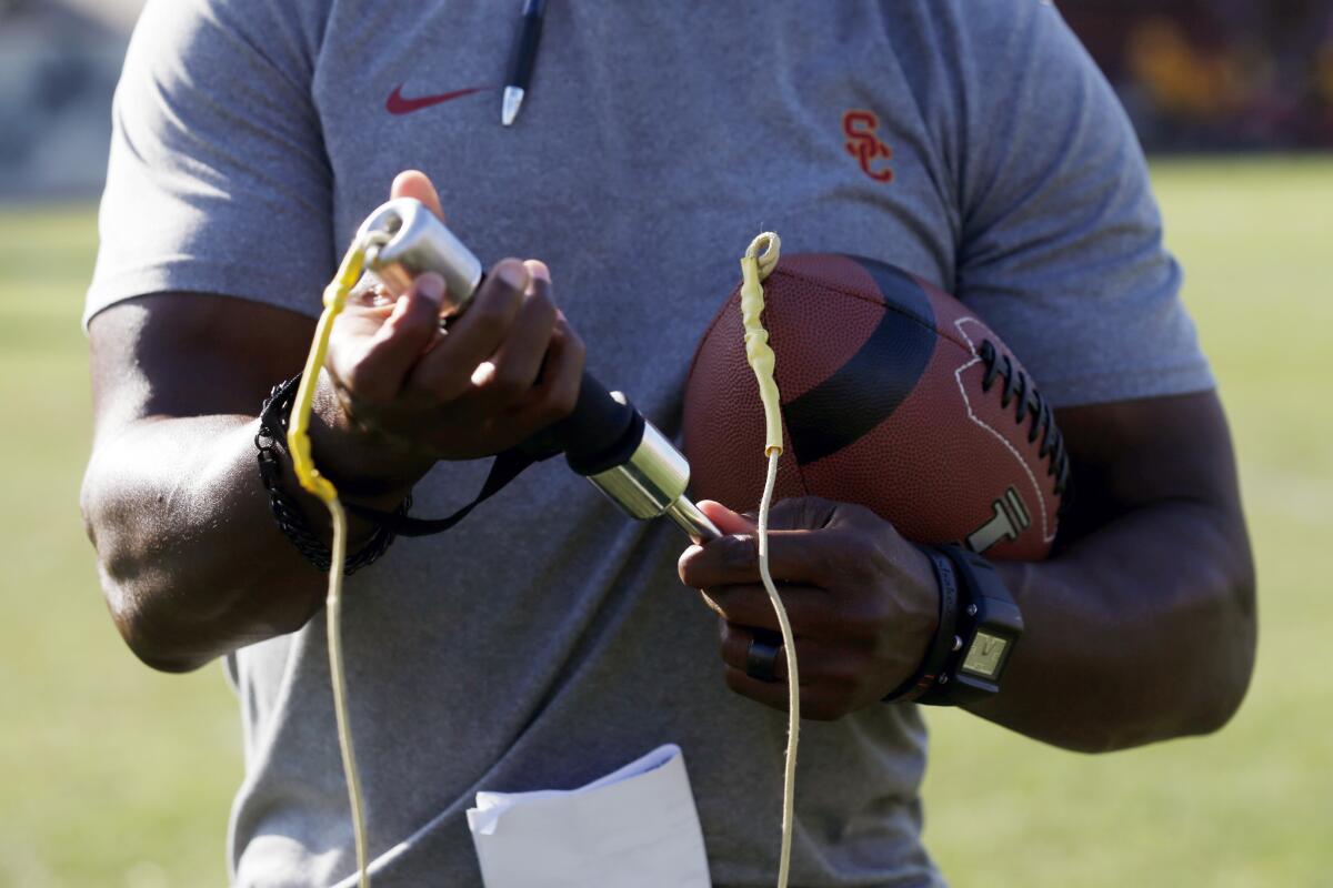 USC running backs coach Deland McCullough is shown with the Fumble Pro, used to improve ball security, after practice Thursday.