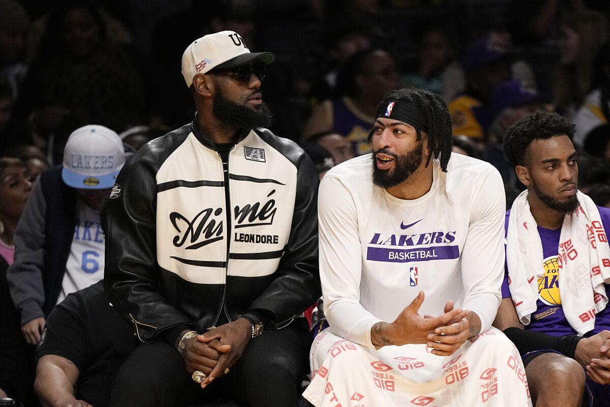 The Lakers' LeBron James, left, and Anthony Davis chat as they sit on the bench during the first half March 24, 2023.