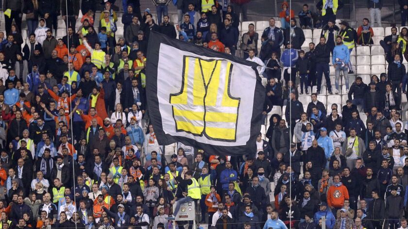 A member of the crowd waves a flag representing a giant yellow vest in solidarity with demonstrators protesting against rising fuel taxes during a League One soccer match in Marseilles on Sunday.