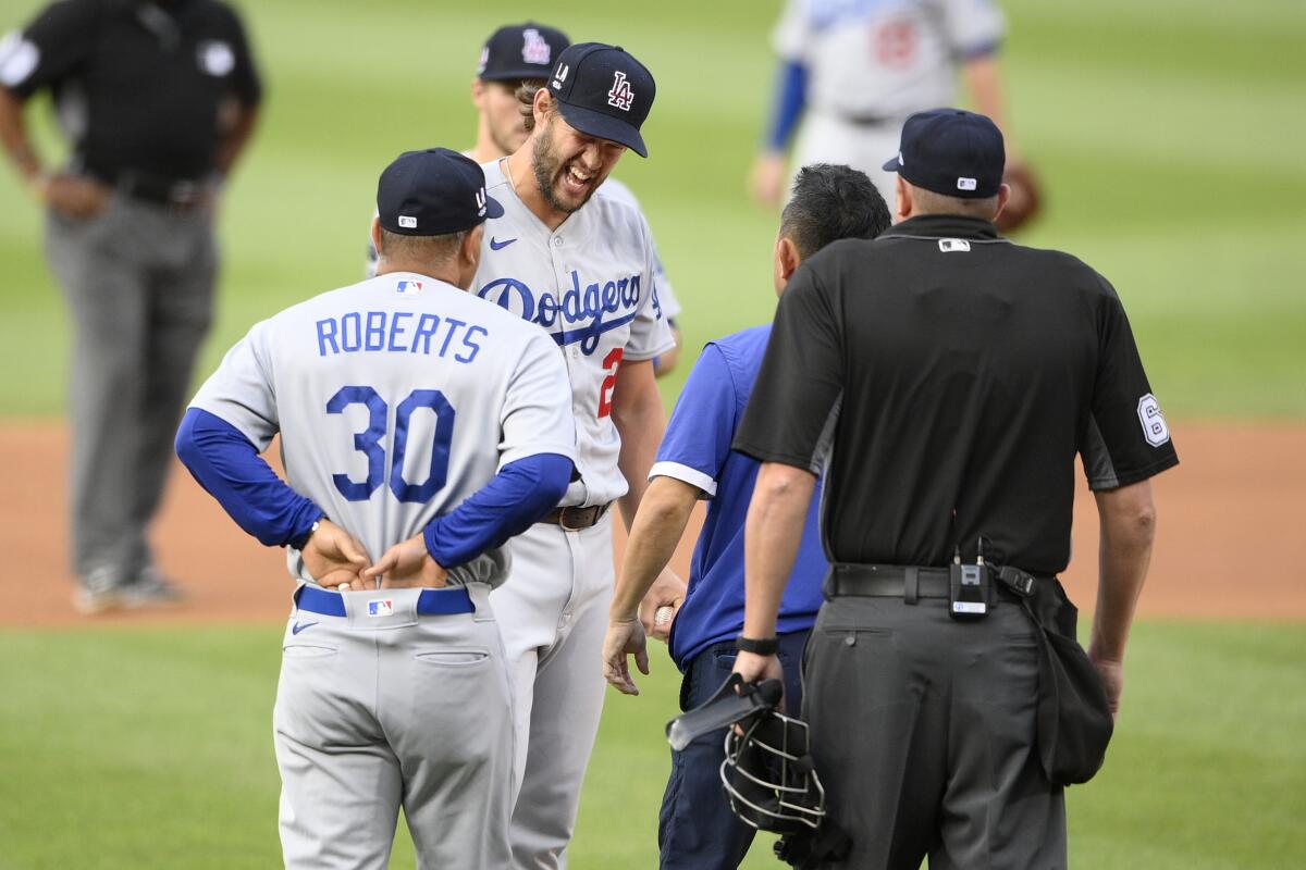 Dodgers starting pitcher Clayton Kershaw, second from front left, is checked out by manager Dave Roberts and a trainer.