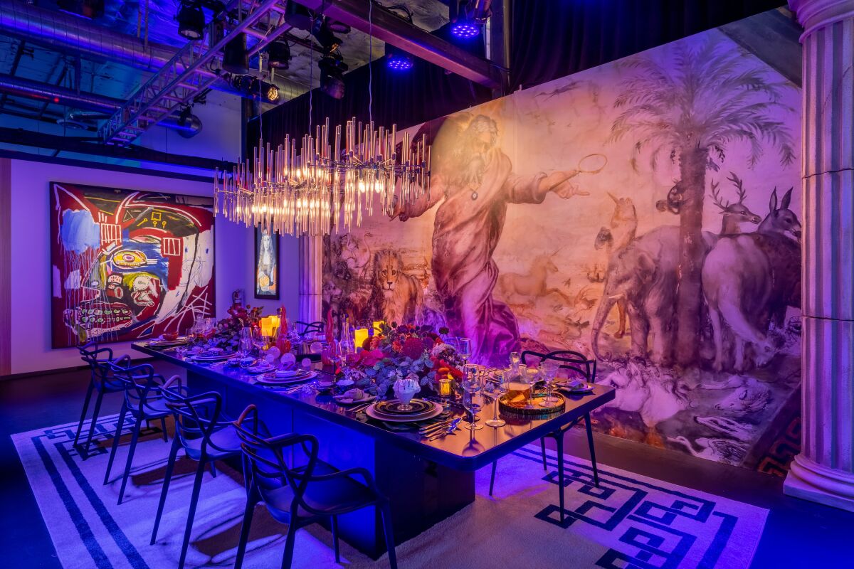 A table set for dinner for eight, with large paintings on two walls behind it