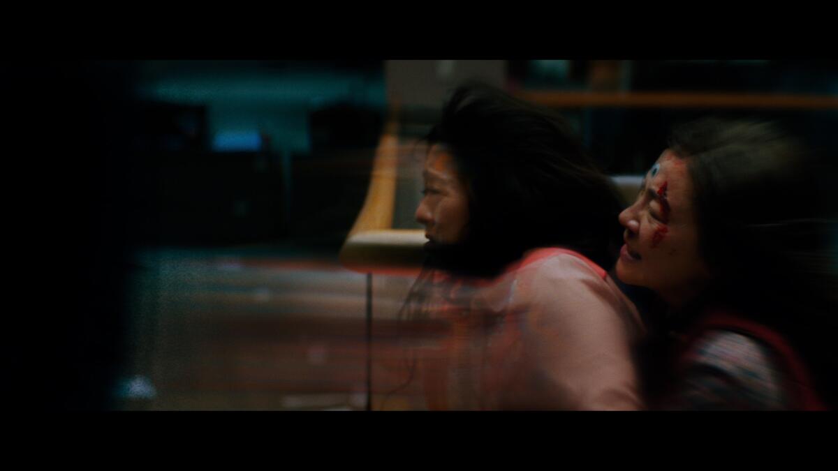 A blurred image shows one woman holding onto the other from behind in a scene from "Everything Everywhere All at Once."