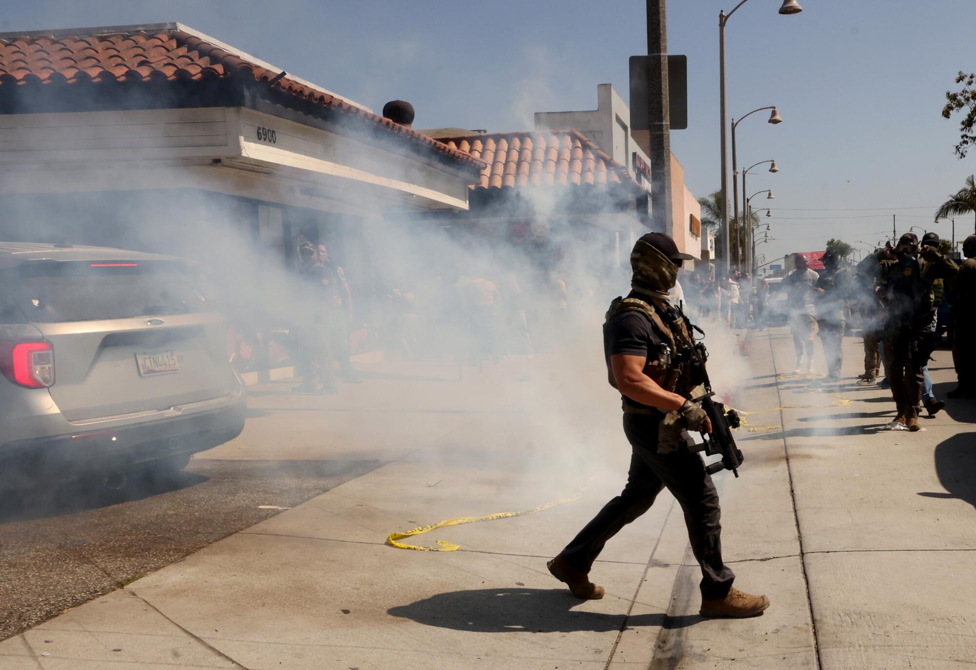 A Federal agent walks through tear gas that was fired to push protesters back.