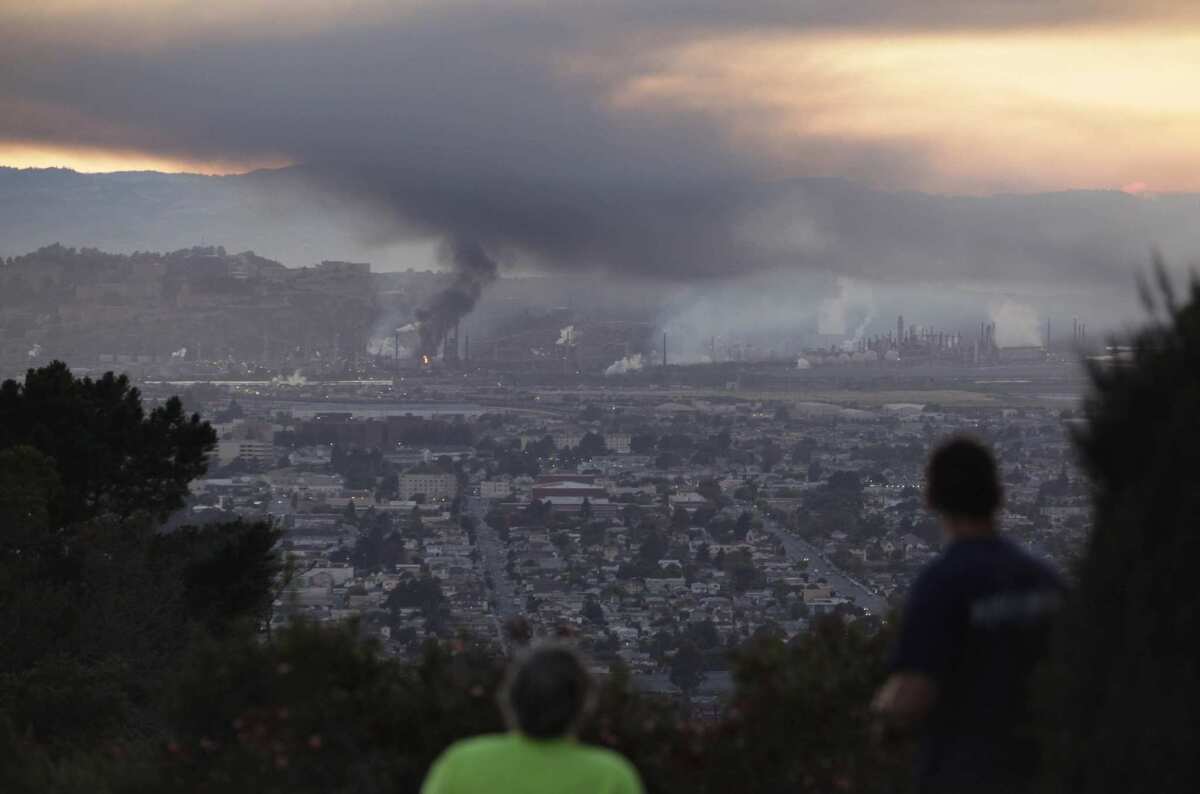 People watch smoke rise from the Chevron refinery in Richmond, Calif.