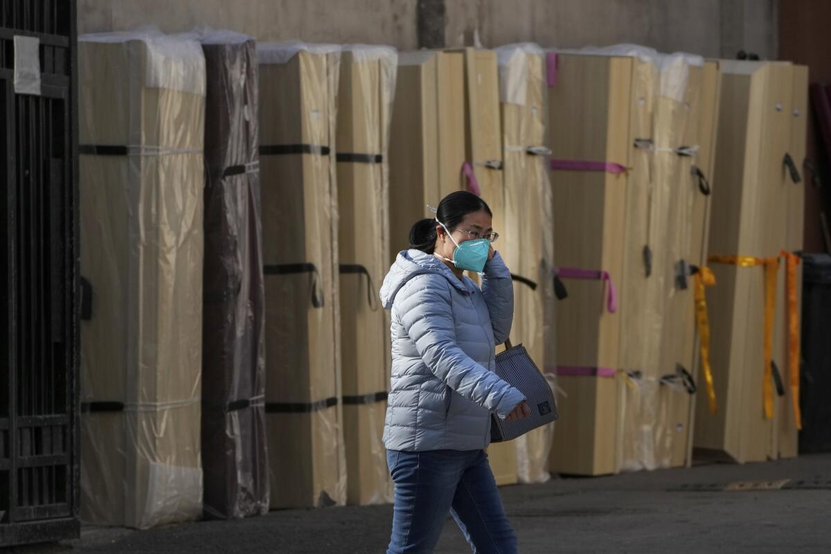 Una mujer con mascarilla pasa junto a ataúdes vacíos almacenados en el exterior de una morgue de un hospital de Beijing
