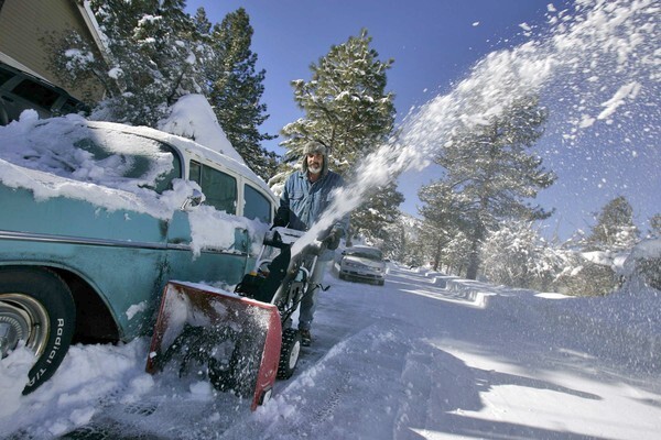 Leon Heilman uses a snowblower to clear the street in front of his home in Wrightwood.