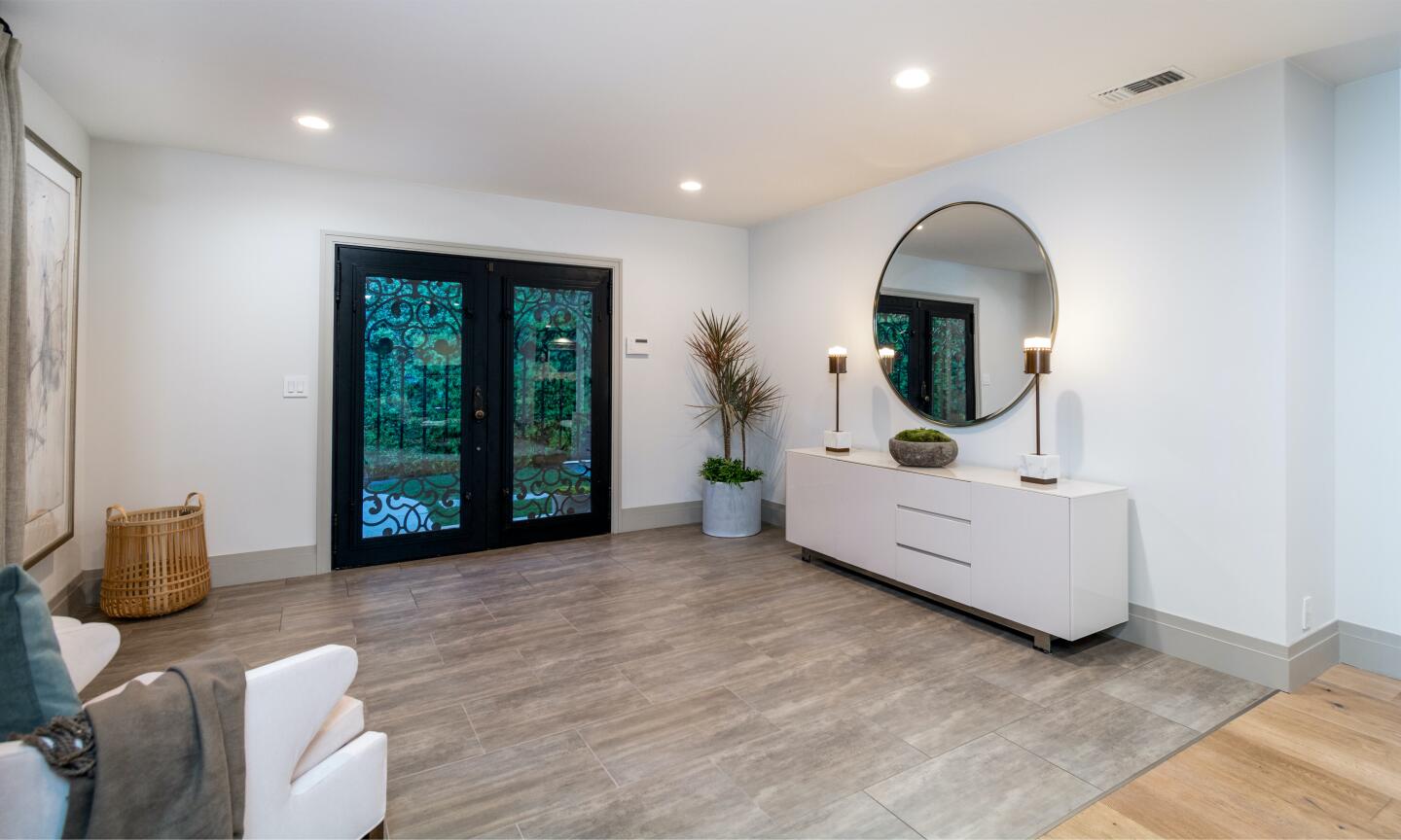 The entry with glass doors, a mirror and side cabinet.