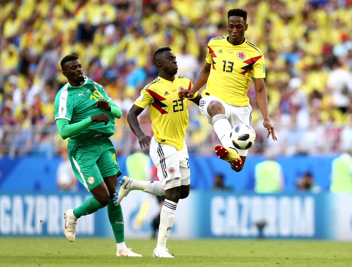 Colombia's Yerry Mina (13) controls the ball next to teammate Davinson Sanchez and Senegal's M'Baye Niang.