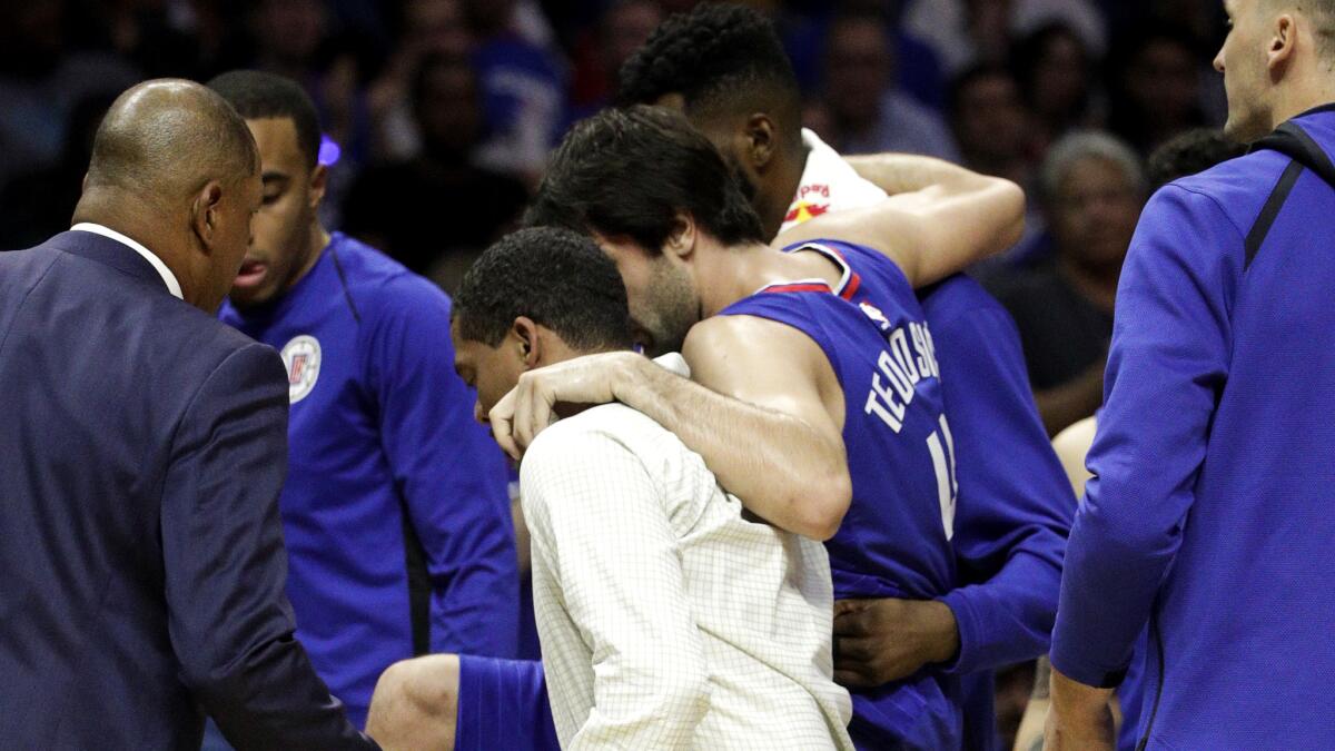Clippers forward Milos Teodosic is carried off the court after injuring his left foot during the game against the Suns on Saturday night.