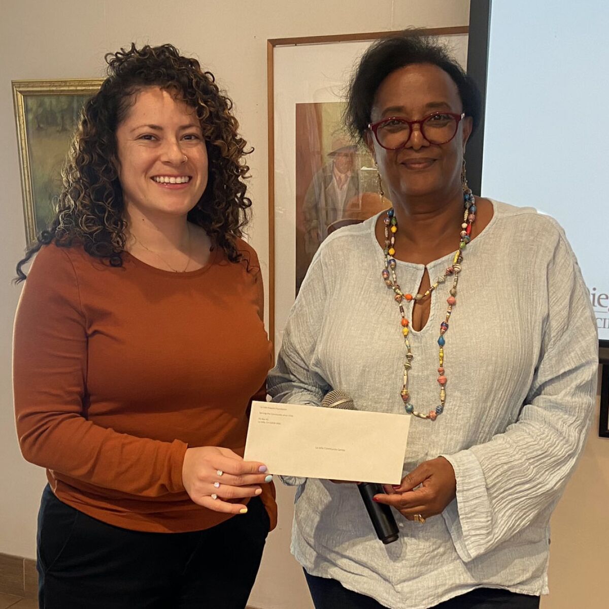 Debbie Miller (left) from the La Jolla Community Center receives a check for $8,000 from Kedest Behanu.