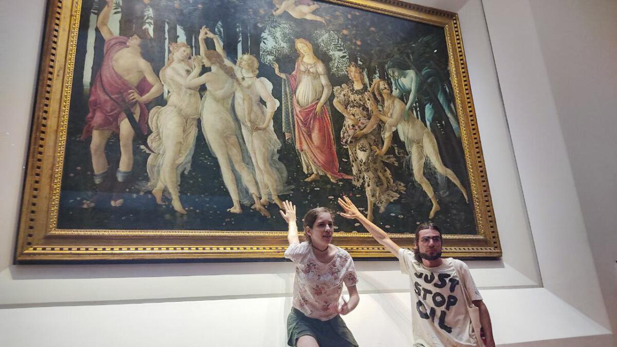 Two activists of Ultima Generazione (Last Generation) environmentalist group claim to glue themselves to the glass protecting Italian Renaissance painter Sandro Botticelli's Primavera (Spring) in Florence's Uffizi Galleries, central Italy, Friday, July 22, 2022. Carabinieri police said two Italian young women and a man sat on the floor in the Uffizi's Botticelli room and displayed a banner reading, "Last Generation No Gas No Coal" . The museum said thanks to the glass the masterpiece was unharmed. (Ultima Generation via AP)(Ultima Generation via AP)