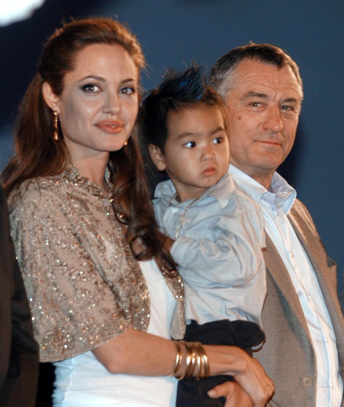 Angelina Jolie cradles her son Maddox alongside actor Robert De Niro at a Sept. 10, 2004, screening of "Shark Tale" at the Venice Film Festival.