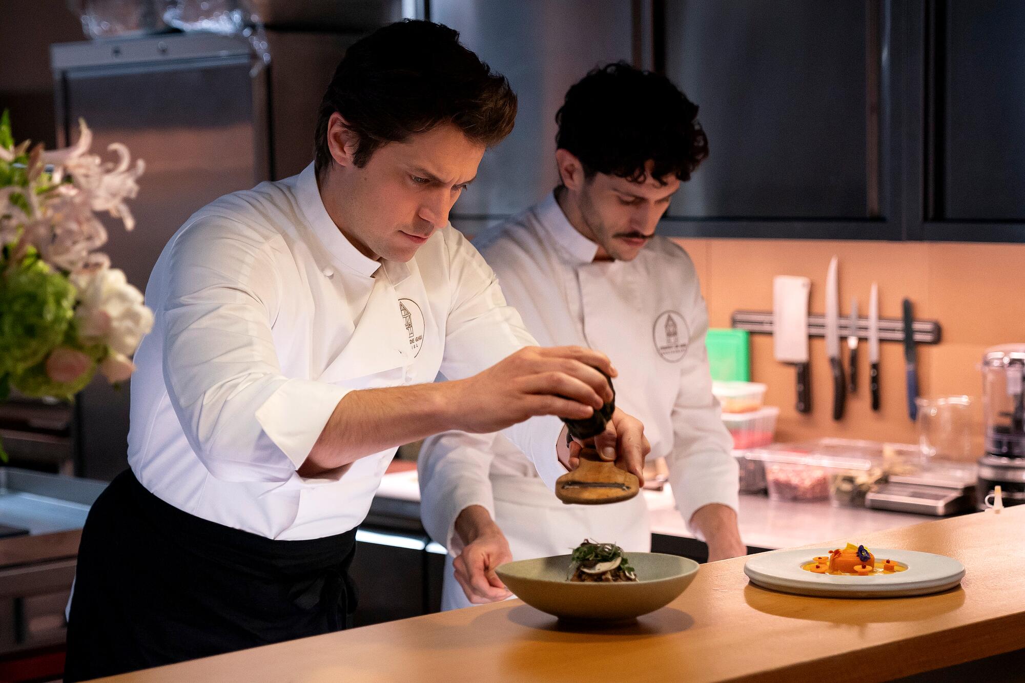 Two men in chef uniforms in a kitchen