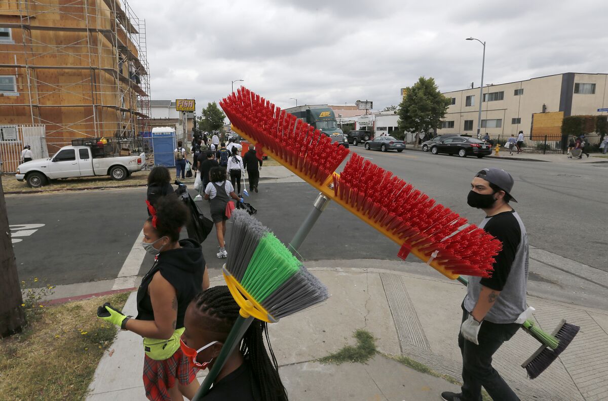Volunteers carrying brooms participate in Friday's cleanup.