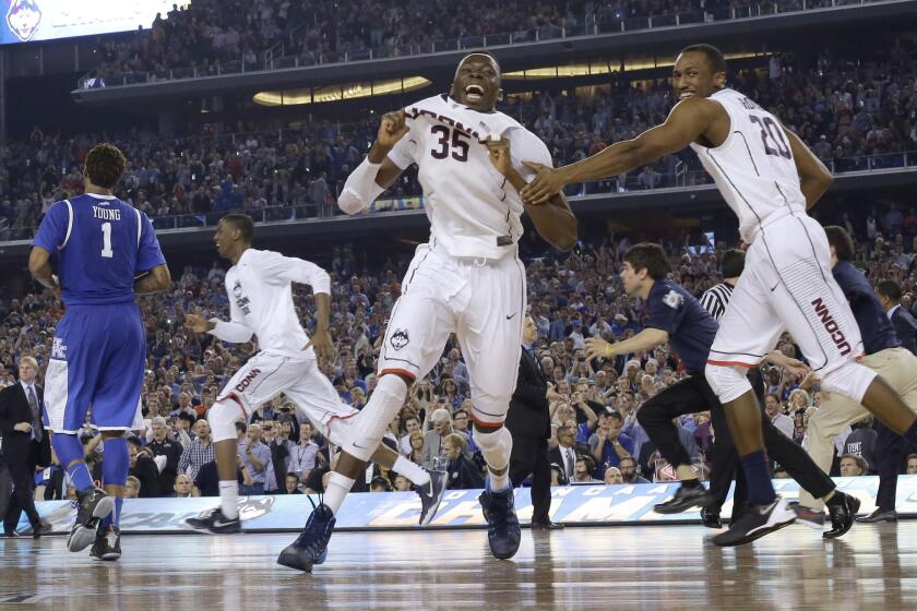 Connecticut players including center Amida Brimah (35) and guard Lasan Kromah (20) celebrate as Kentucky guard James Young (1) leaves the court at the end of the NCAA Tournament college basketball championship game last year in Arlington, Texas. Connecticut won 60-54.