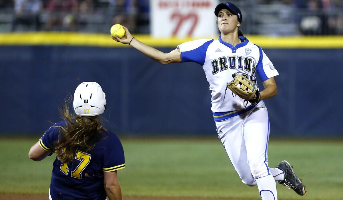 UCLA's Gracie Goulder throws to first to complete a double play as Michigan's Haylie Wagner slides into second base during the NCAA Women's College World Series on Friday.