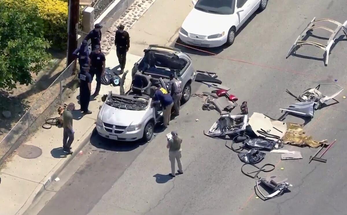 Aerial view of people looking into a minivan, with parts of the van strewn in the road.