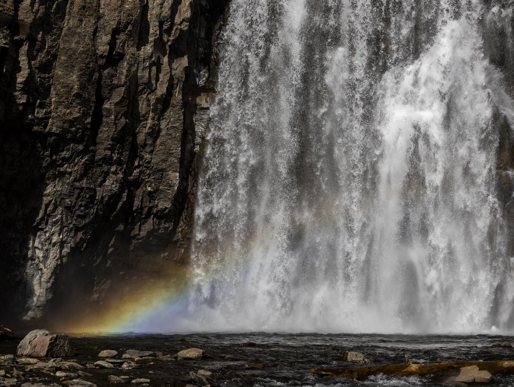 A rainbow at the base of a tumbling waterfall.