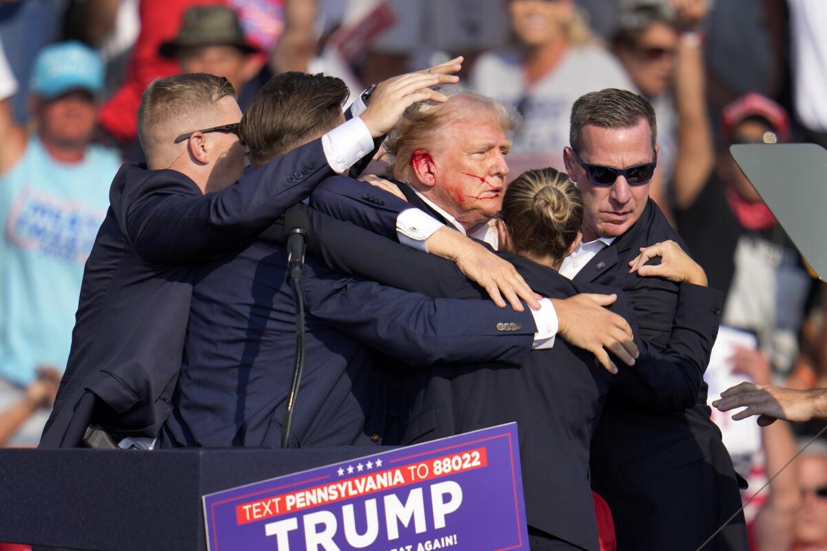 Former President Trump is surrounded by Secret Service agents during a campaign rally on Saturday in Butler, Pa.