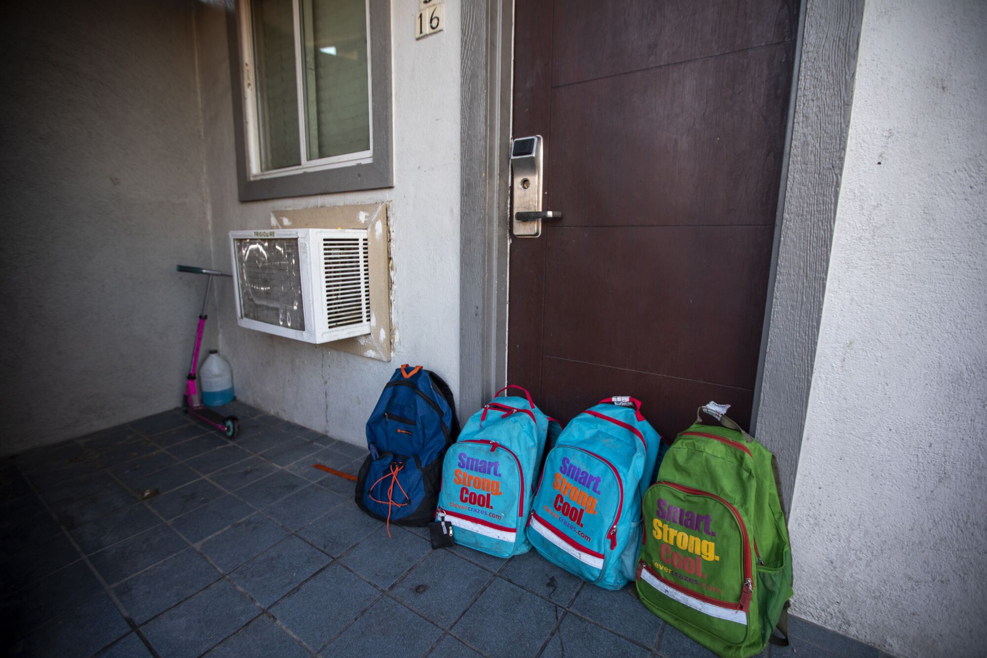 School backpacks are lined up outside a door