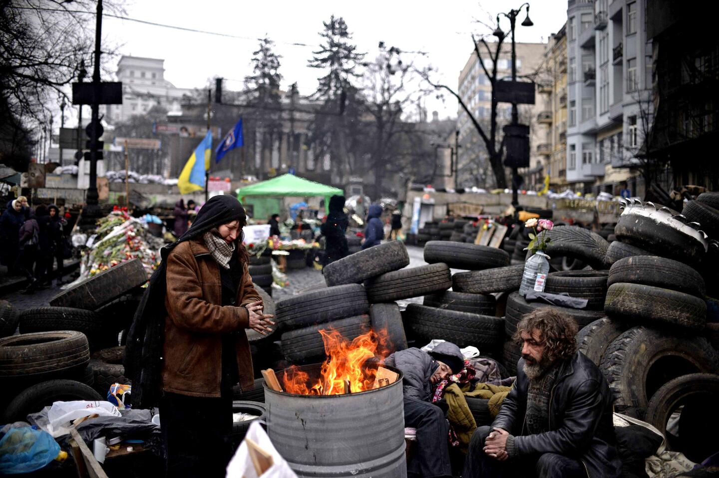 A member of a "self-defense" unit warms up by a stove at a barricade near Independence Square in central Kiev this month.