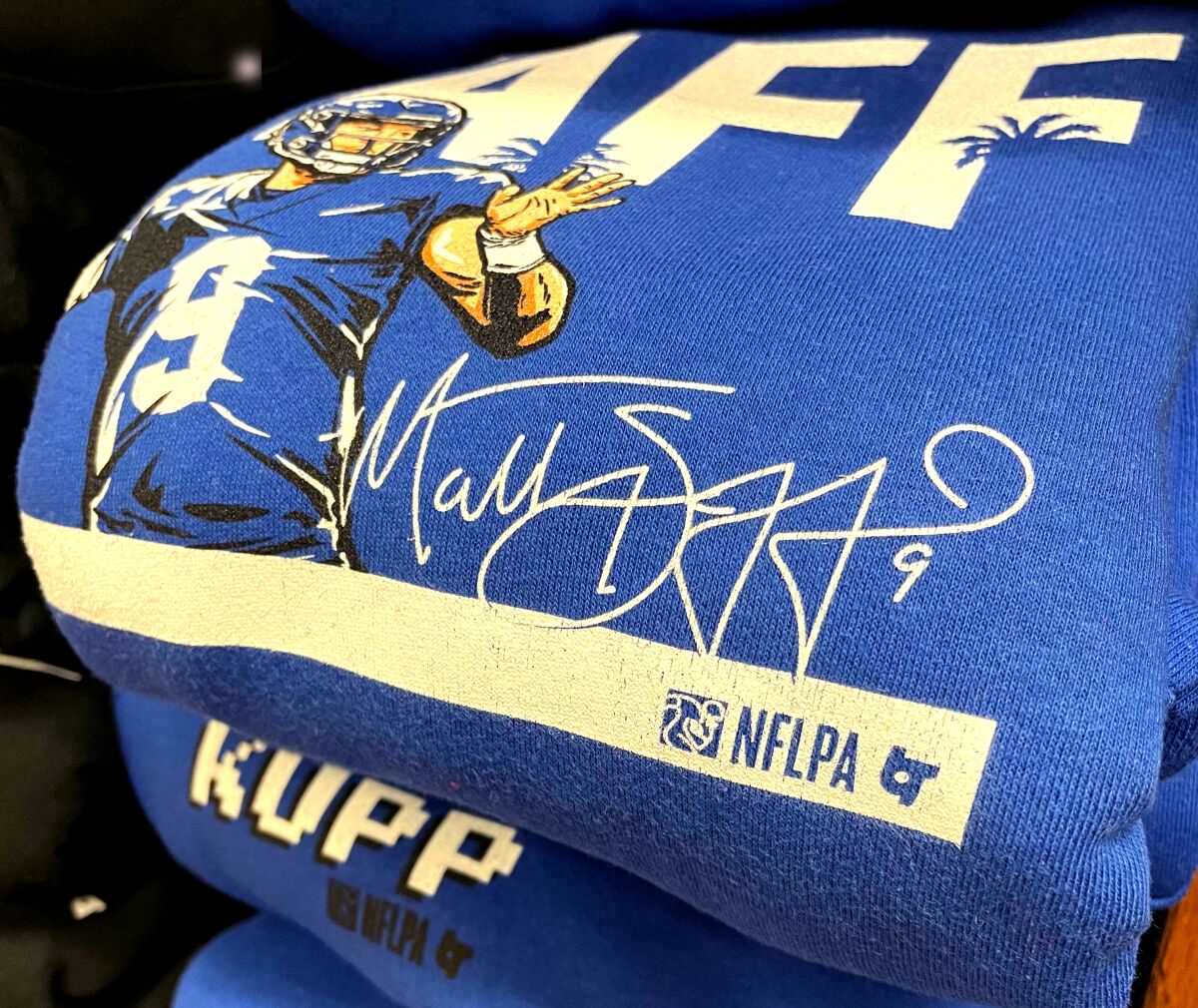 A stack of sweatshirts from BreakingT celebrating Rams stars Cooper Kupp and Matthew Stafford.
