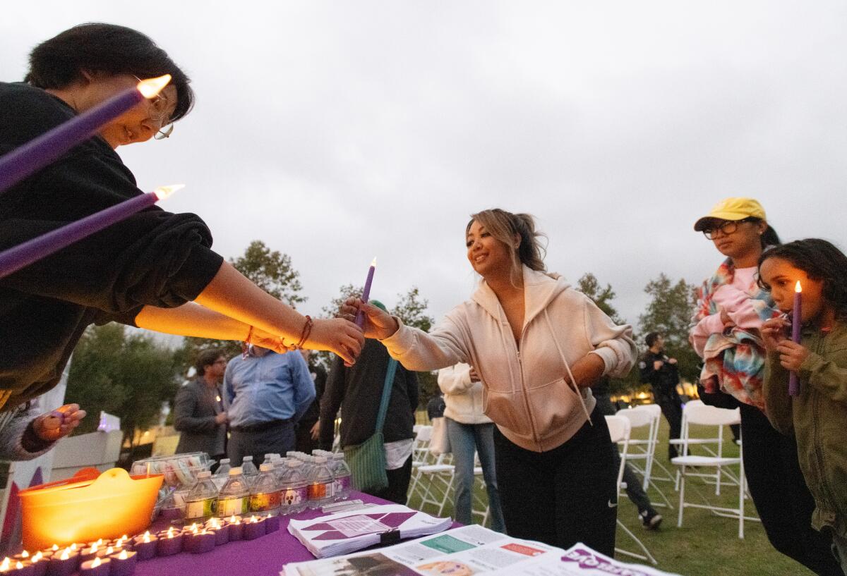 Volunteers hand candles to attendees of the Shine the Light walking vigil held Wednesday at Lions Park.