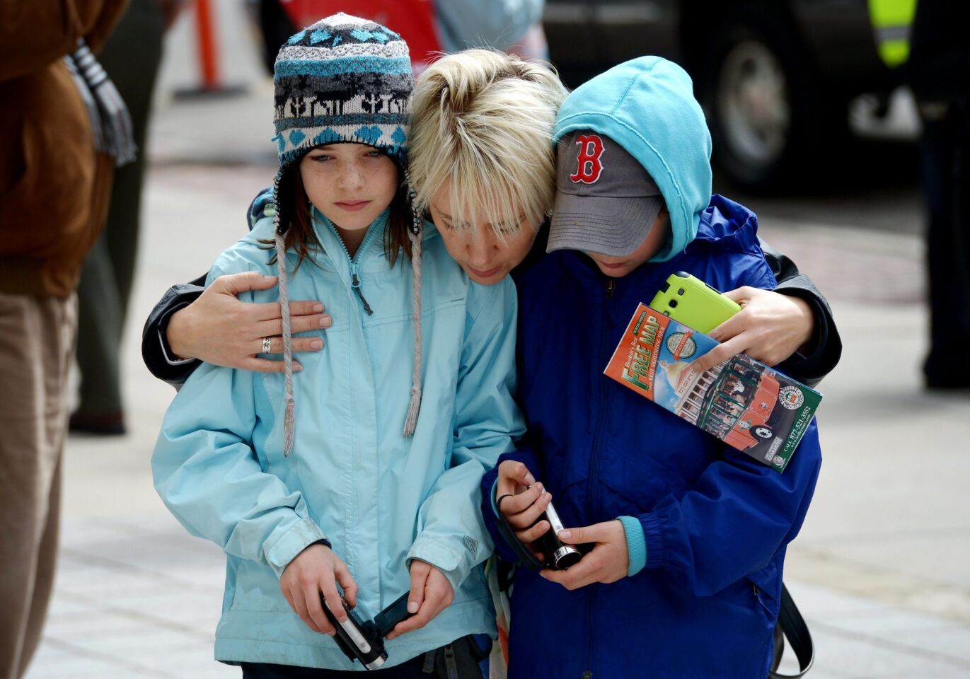 A woman and two children gather at the site of the first bombing near the finish line of the Boston Marathon on Boylston Street in Boston.