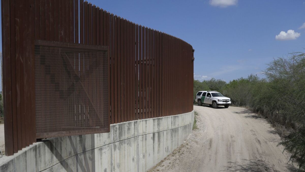 In this Aug. 11, 2017, photo, a U.S. Customs and Border Protection vehicle passes by a section of the border wall in Hidalgo, Texas.