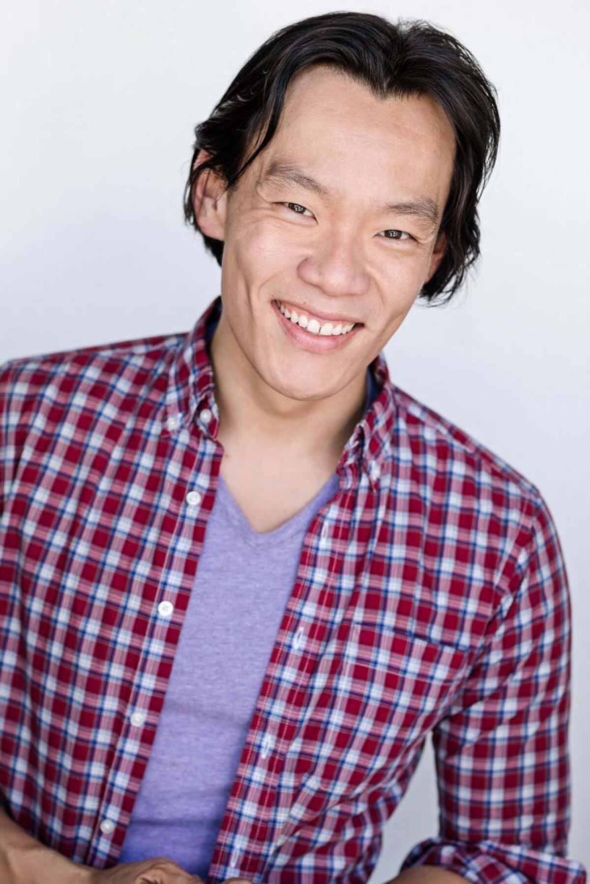 A headshot of a smiling man wearing a plaid shirt.