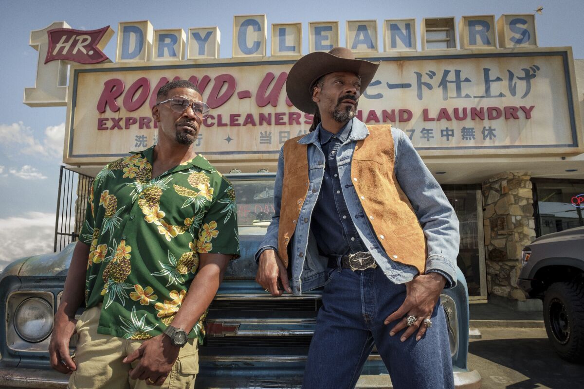 This image released by Netflix shows Jamie Foxx, left, and Snoop Dogg in a scene from "Day Shift." (Andrew Cooper/Netflix via AP)