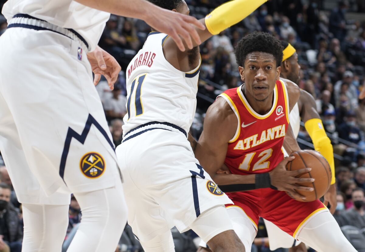 Atlanta Hawks forward De'Andre Hunter, right, looks to pass the ball as Denver Nuggets guard Monte Morris defends during the first half of an NBA basketball game Friday, Nov. 12, 2021, in Denver. (AP Photo/David Zalubowski)