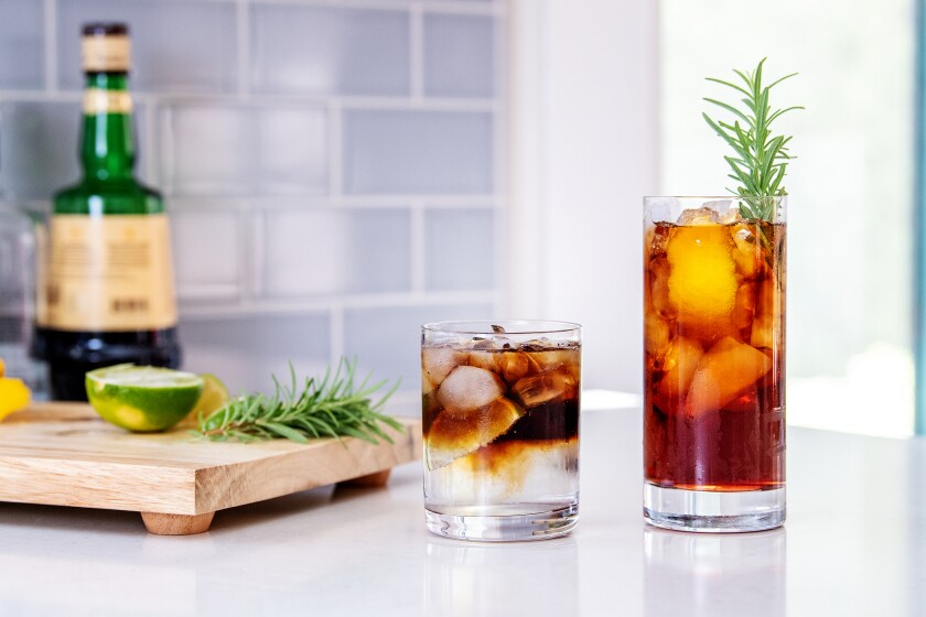 A cutting board with ingredients, left, and two coffee tonic cocktails in glasses.