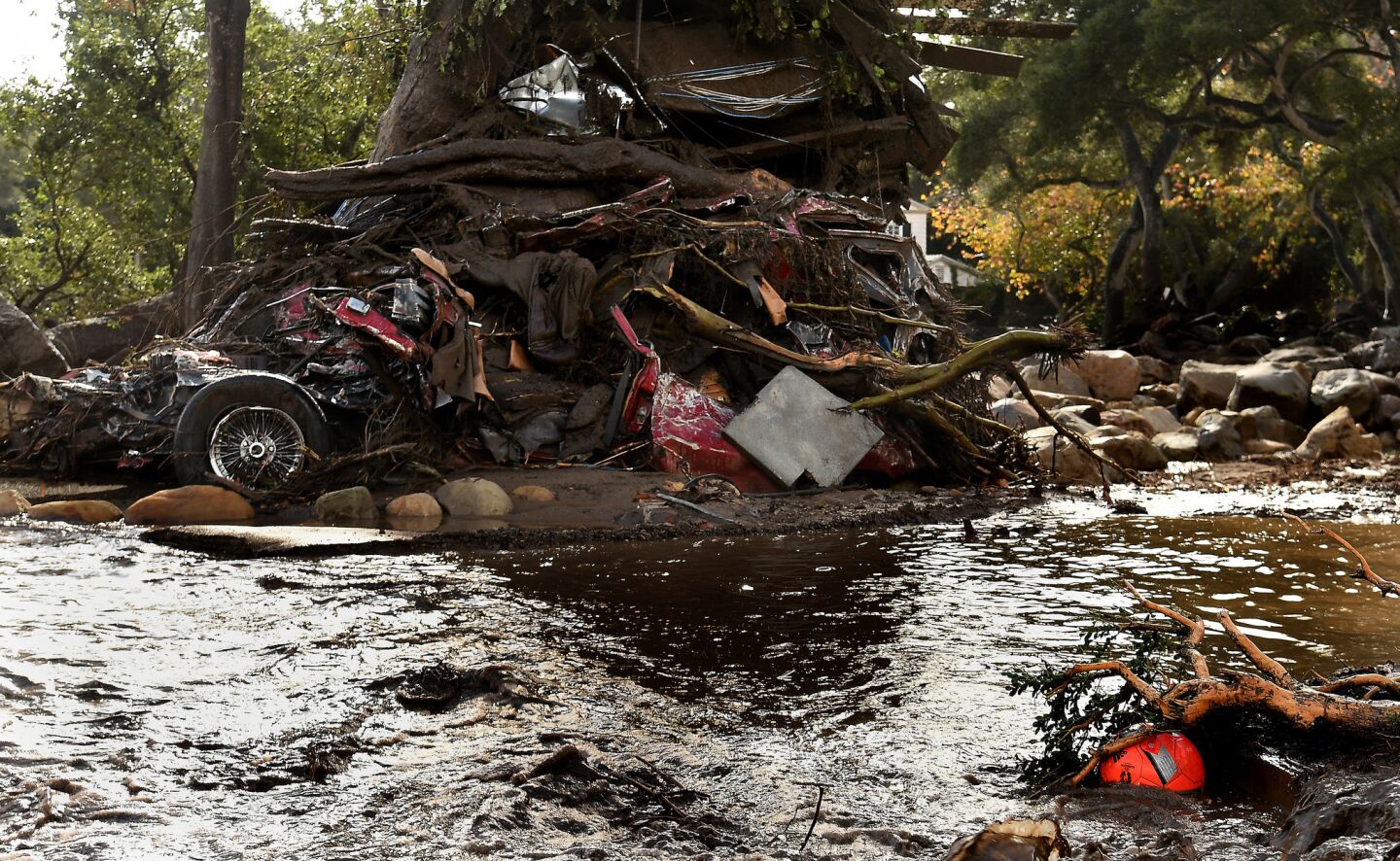 A mangled car along with other debris is wrapped around a tree along Hot Springs Road in Montecito.