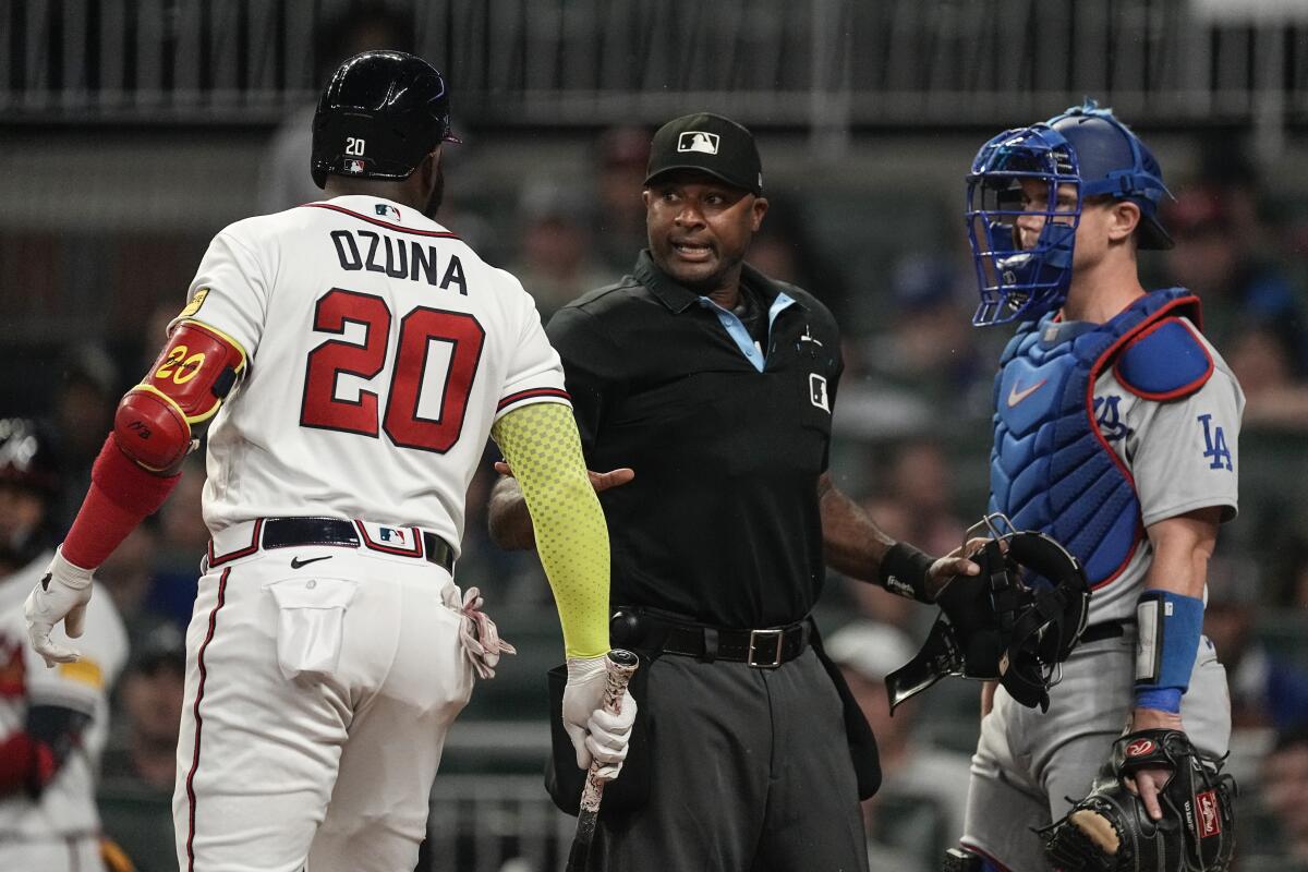 Home plate umpire Alan Porter gets between the Braves' Marcell Ozuna and the Dodgers' Will Smith as they exchange words.