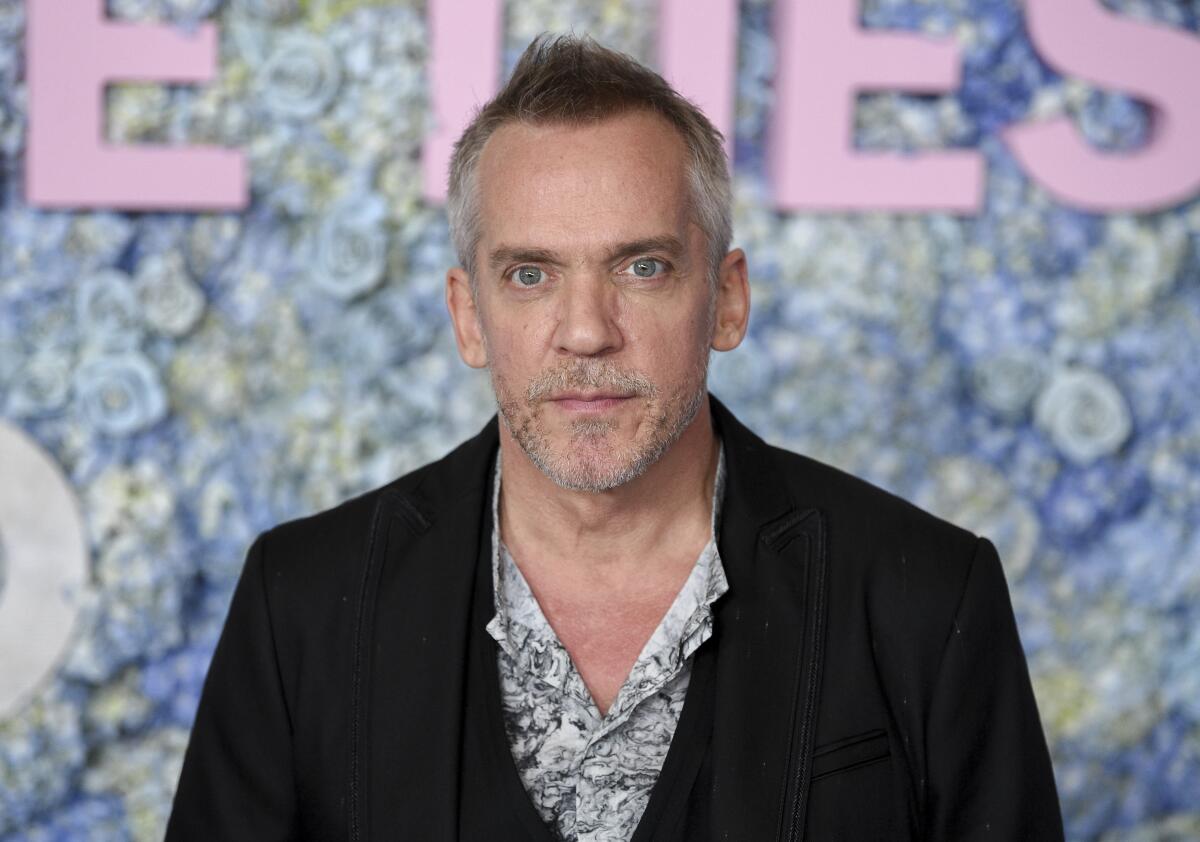 A man wearing a floral shirt and dark blazer