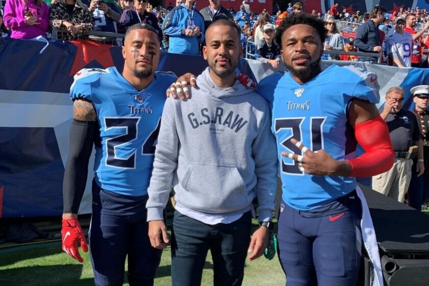 David Mulugheta is flanked by Titans players Kenny Vaccaro, left, and Kevin Byard. .