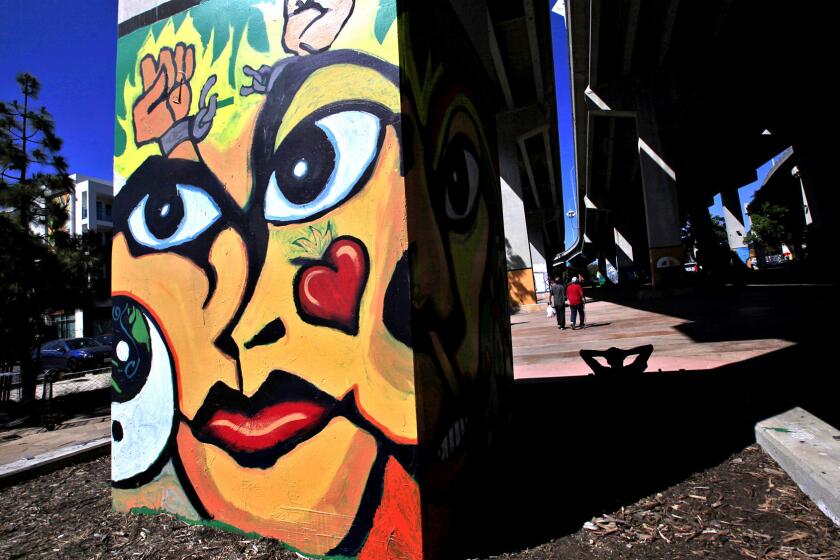 Barrio Logan residents walk past columns covered with murals through Chicano Park under the Coronado Freeway bridge near Newton Avenue. The park was created after the bridge cut the community in half and residents pressured the government to give them some green space.